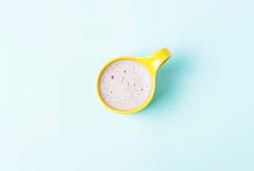 yellow Cup of coffee on a blue background, top view