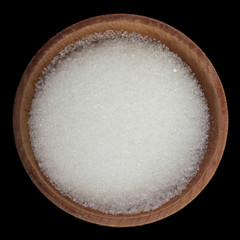 heap of sugar in wooden cup isolated on black background. top view