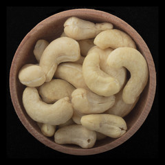 cahhew in wooden cup isolated on black background. top view