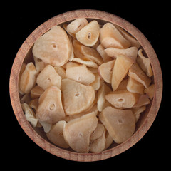 dried slices of garlic in wooden cup isolated on black background. top view