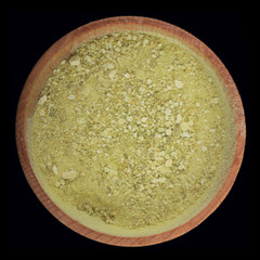 dried ground lime  in wooden cup isolated on black background. top view