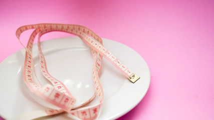 white dish tape measure  on pink background
