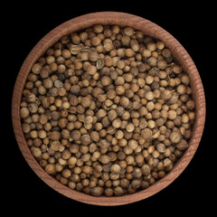 coriander seeds  in wooden cup isolated on black background. top view
