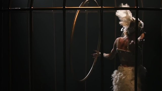 Acrobatics aerial on a rotating hoop in a metal cage . Black background. Slow motion. Close up
