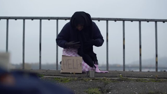 Homeless beggar asking for help, adult woman begging on the street.