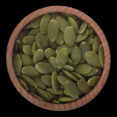 seeds of pumpkin  in wooden cup  isolated on black background. top view