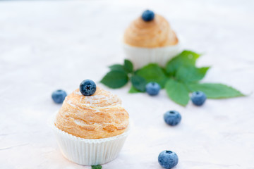 Fresh baked golden muffins with blue berries on rustic wooden background shot in natural light
