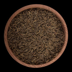 caraway  in wooden cup isolated on black background. top view