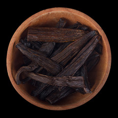vanilla in wooden cup isolated on black background. top view