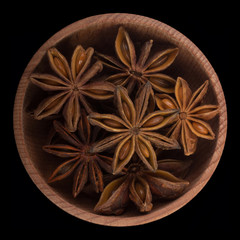 badian in wooden cup isolated on black background. top view