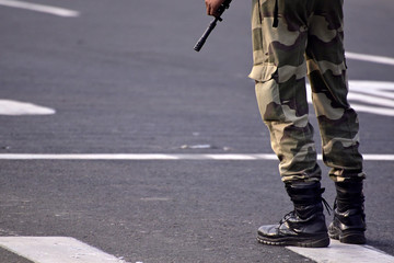 Security guard with rifle standing on outside to protect the area.