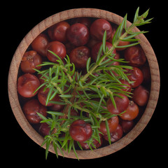 red juniper berries  in wooden cup isolated on black background.  top view