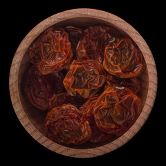 dried slices of dried tomatoes  in wooden cup isolated on black background.  top view
