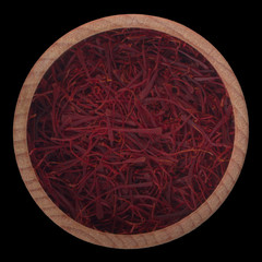 red fresh saffron in wooden cup isolated on black background.  top view