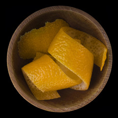 rind of orange in wooden cup isolated on black background.  top view