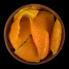 rind of orange in wooden cup isolated on black background.  top view