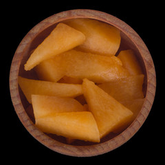 Cantaloupe slices in wooden cup isolated on black background.  top view