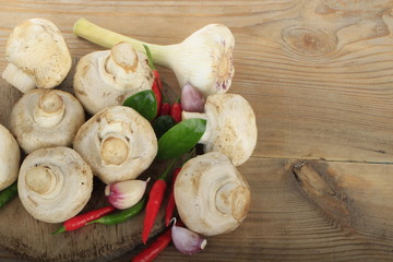 champignons with spices on wooden background