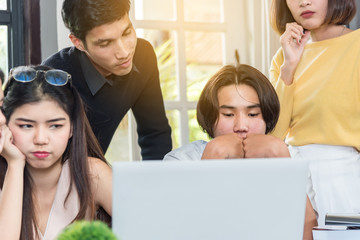 Group of young colleagues Serious team working together around a laptop in the meeting room at office