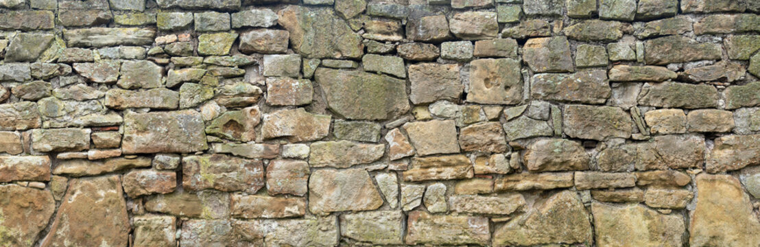 Panorama einer groben, sehr alten Natursteinmauer aus unterschiedlich gro&szlig;en Steinen