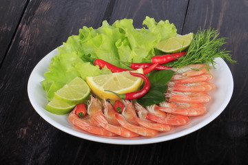 cooced prawns with spices in plate on wooden background