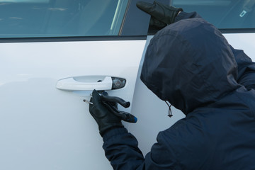 burglar in black clothes, illegally opened the car door, mechanically