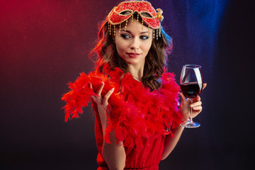 Seductive woman in red fancy dress holding a glass of wine looks languid.- Image