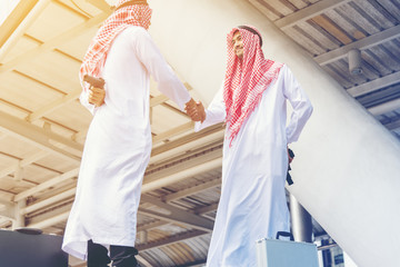 Two Arabian Businessman shaking hand after discussed while other people holding gun in hands double-cross ,blackmail business concept