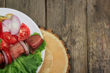 kebab with lettuce and tomatoes on wooden background