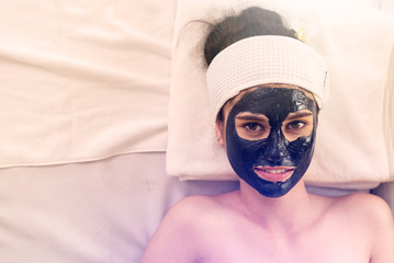 Close up of Healthy Young Woman getting mud Black facial mask cosmetic procedure in the beauty salon.Skin treatment in spa salon concept