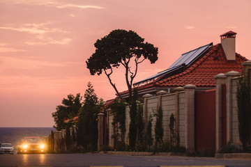 Sunset lights the street with houses near the ocean