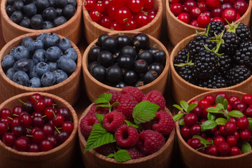 berries in wooden cups on wooden background