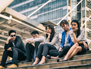 Group of Hopeless depressed business people sitting at stairway outdoor. Bankrupt business people sitting outdoor office. Stressed and Unsuccessful business and financial stock market trading concept.