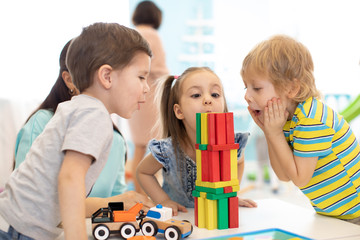 Little kids build wooden toys at home or daycare. Emotional kids playing with color blocks. Educational toys for preschool and kindergarten children.