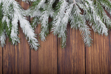 branches of fir with snow on wooden background