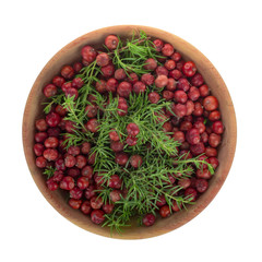 heap of red juniper berries in wooden cup isolated. top view