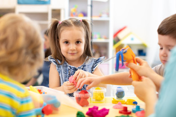 Group of kids playing with modeling clay in nursery - obrazy, fototapety, plakaty