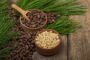 cedar nuts in wooden cups on wooden background