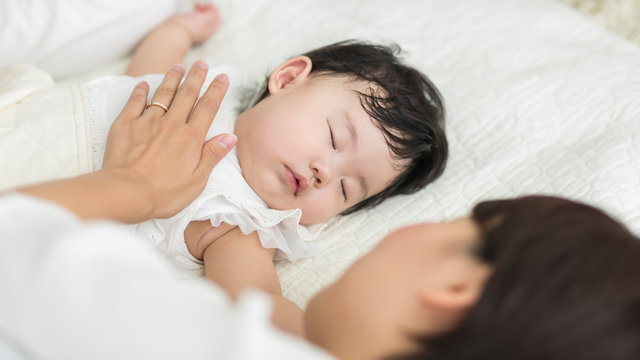 眠る赤ちゃんと見守る母親
