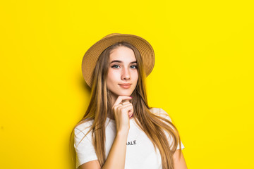 Portrait of charming woman holding hand near face, looking at camera, standing over yellow background