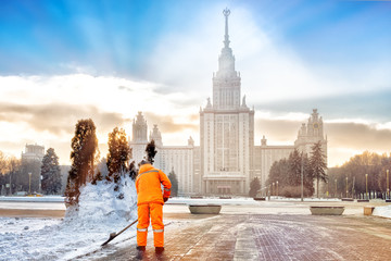 person cleaning snow on street of moscow city historical skyline university tower building...