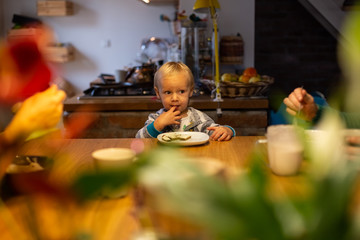 Infant son eating breakfast with family during the morning at the kitchen.