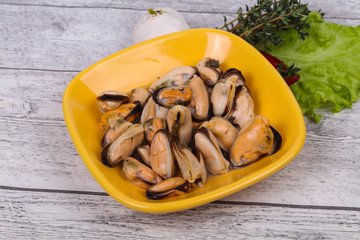 Pickled mussels in the bowl served pepper, garlic and salad