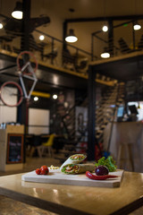 Fototapeta premium Wrap Sandwich on a wooden board with fresh vegetables. 