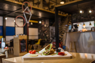 Wrap Sandwich on a wooden board with fresh vegetables. 
