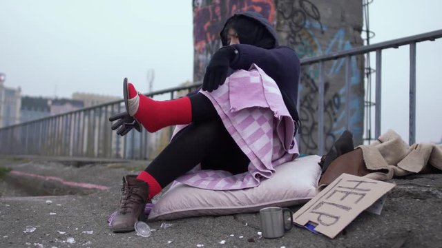 Homeless woman appreciate the shoes worn on a thick red sock.