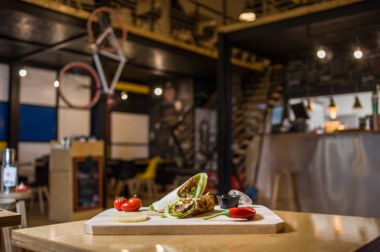Wrap Sandwich on a wooden board with fresh vegetables. 