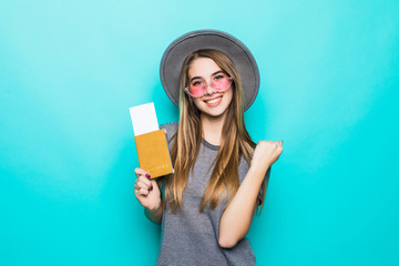 Woman traveler holding passport with ticket. Portrait of smiling happy girl on blue pastel background.