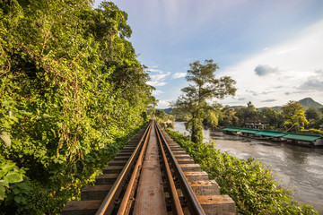 Railway between rocky cliff and river in Kanchanaburi, Thailand