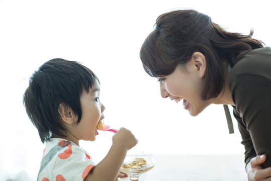 プリンを食べる男の子と見守る母親